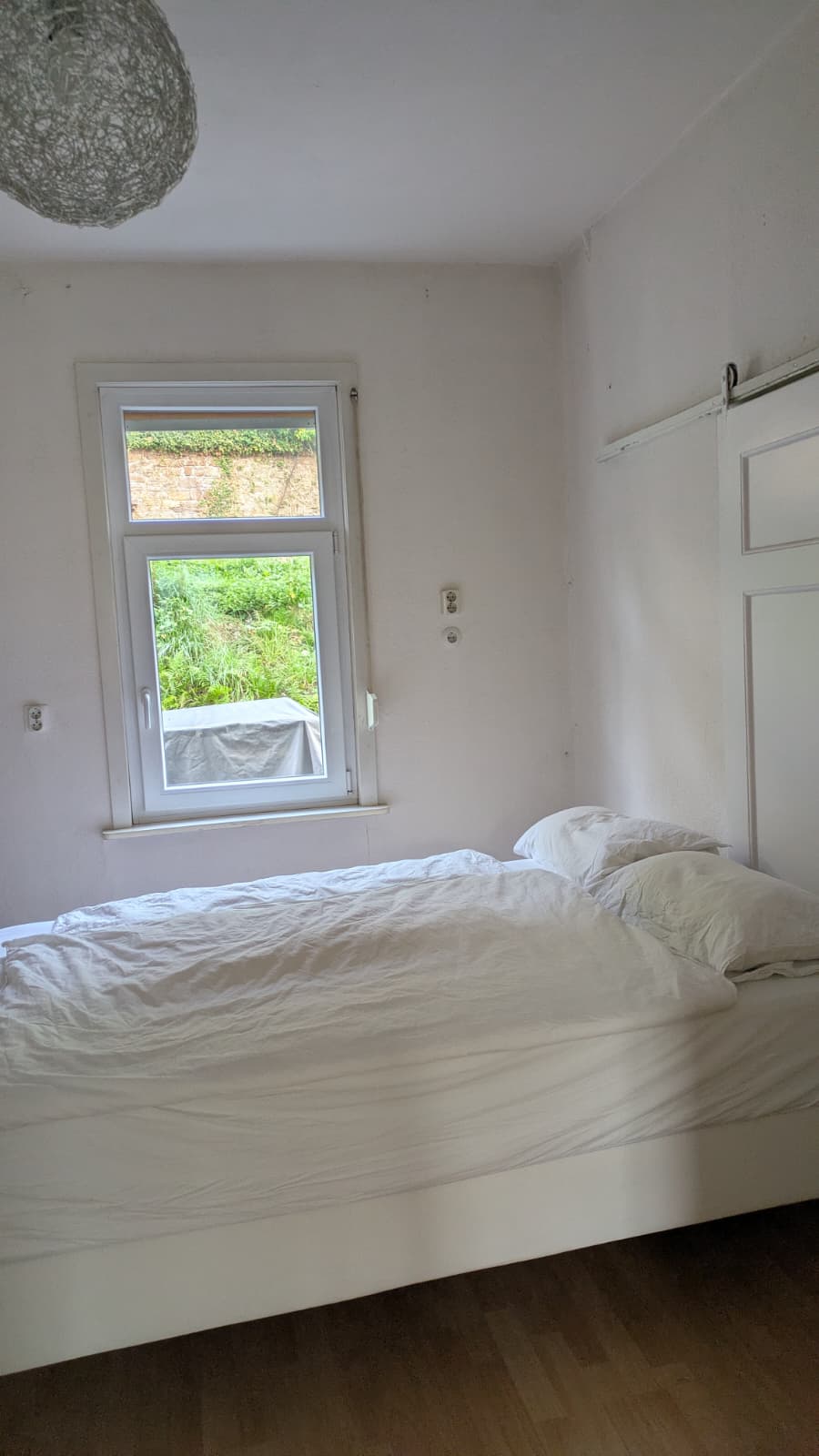 Schlafzimmer mit Bett und Fenster zum Garten